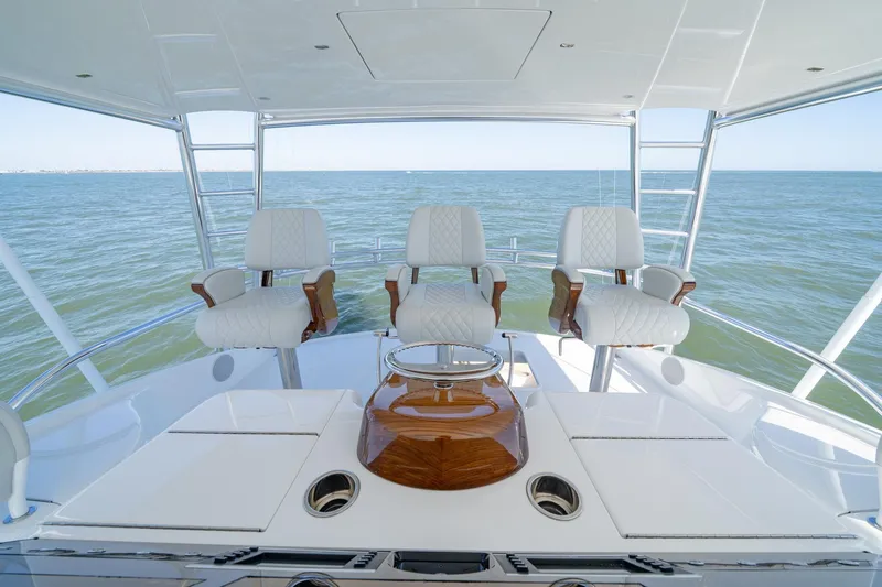 Slide: The Image of 2023 Viking 64 Convertible yacht helm with three white captain chairs overlooking the ocean. - 13
