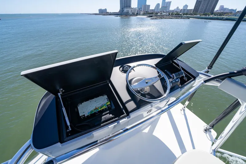 Slide: The Image of 2023 Viking 64 Convertible yacht helm with navigation system, overlooking coastal cityscape. - 18