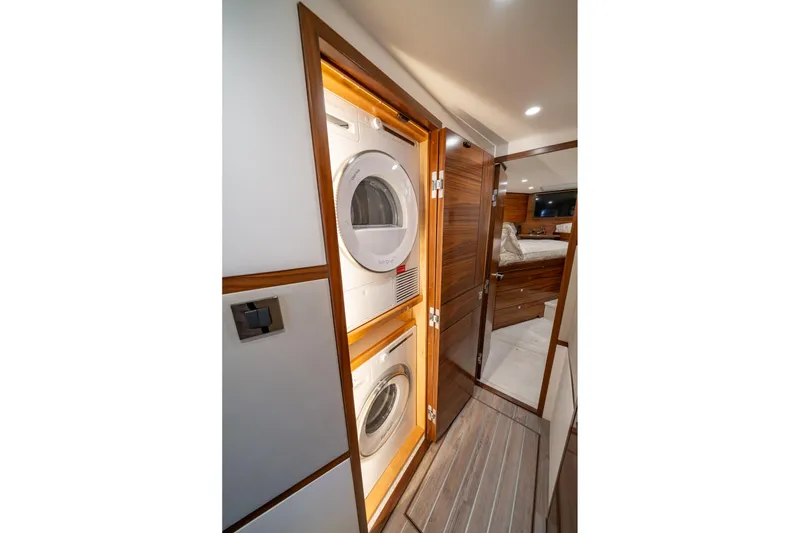 Slide: The Image of Laundry area inside 2023 Viking 64 Convertible yacht with modern wood finish. - 34