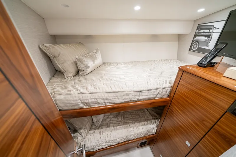 Slide: The Image of 2025 Viking 64 Convertible yacht cabin with bunk beds and modern wood finish. - 38