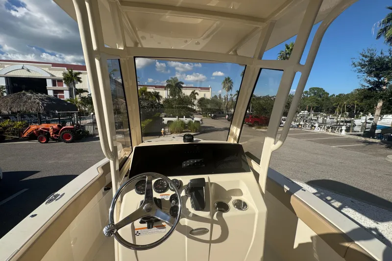 Slide: The Image of 2025 Scout 215 XSF boat dashboard with steering wheel, parked near marina under clear sky. - 11