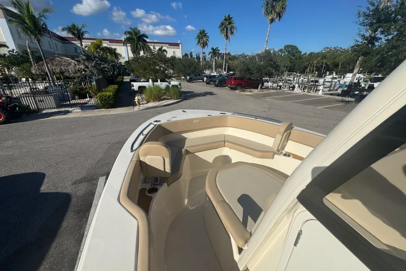 Slide: The Image of 2025 Scout 215 XSF boat with beige seating, parked near palm trees and a marina. - 4