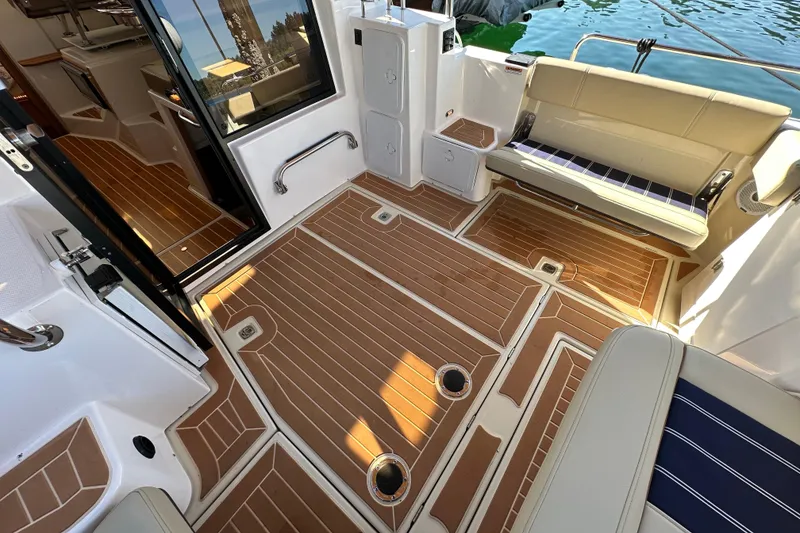 Slide: The Image of 2020 Ranger Tugs R-29 boat interior with teak flooring and cushioned seating. - 8