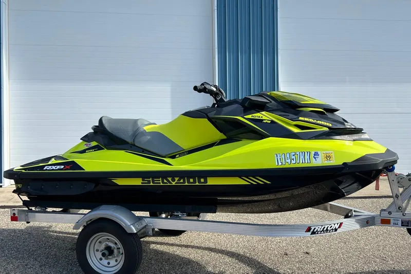 The Image of 2018 Sea-Doo RXP-X 300 jet ski in vibrant yellow on a trailer. - 1