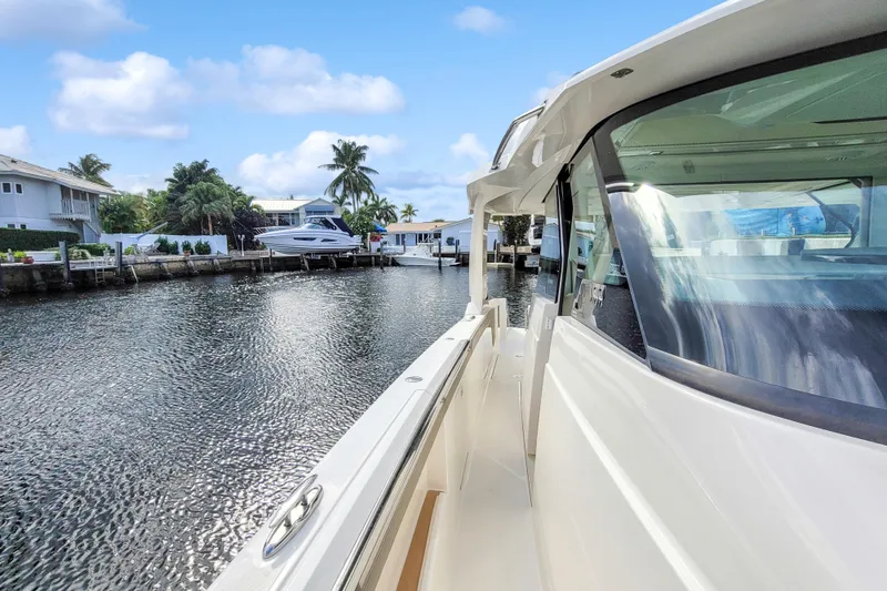 Slide: The Image of 2022 Tiara Yachts 48 LS docked by waterfront homes under a clear blue sky. - 10