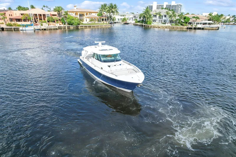 Slide: The Image of 2022 Tiara Yachts 48 LS cruising on a scenic waterfront with luxury homes. - 2