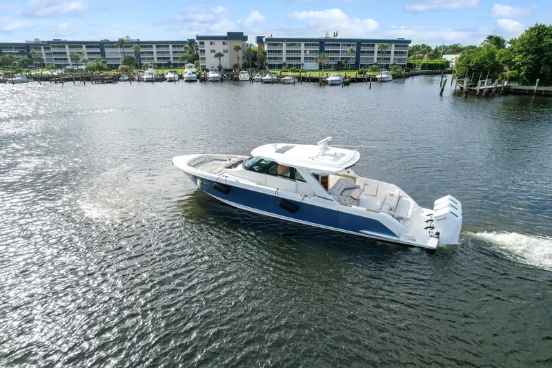 Slide: The Image of 2022 Tiara Yachts 48 LS cruising on a scenic waterfront with modern buildings. - 4