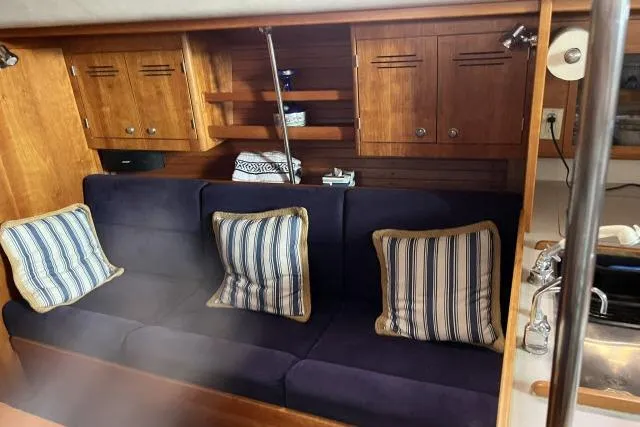 Slide: The Image of 2004 J Boats J/133 interior with blue sofa, striped cushions, and wooden cabinetry. - 3