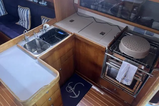 Slide: The Image of 2004 J Boats J/133 yacht interior kitchen with sink, stove, and wooden cabinetry. - 5