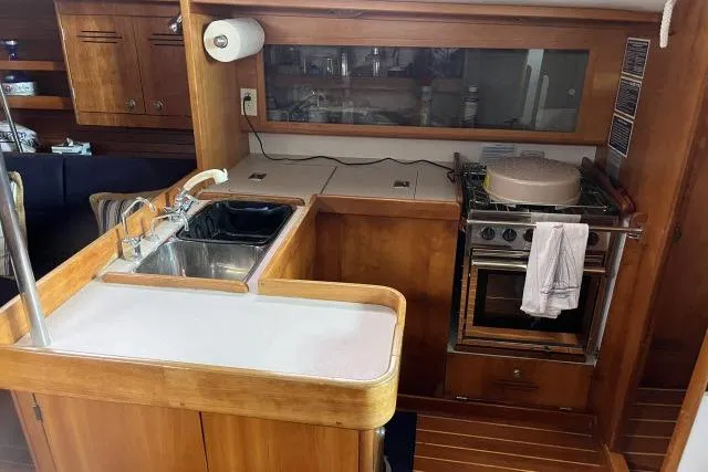 Slide: The Image of 2004 J Boats J/133 yacht interior kitchen with sink, stove, and wooden cabinetry. - 6