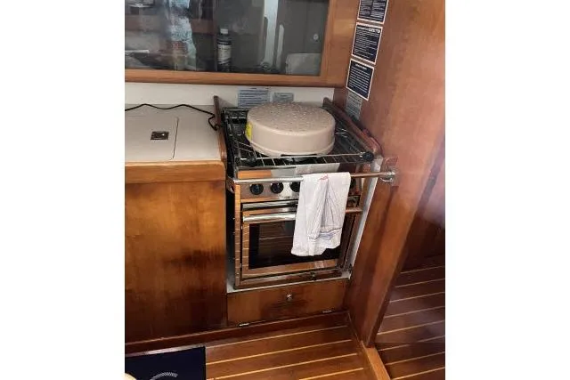 Slide: The Image of 2004 J Boats J/133 yacht interior with stove and wooden cabinetry. - 8