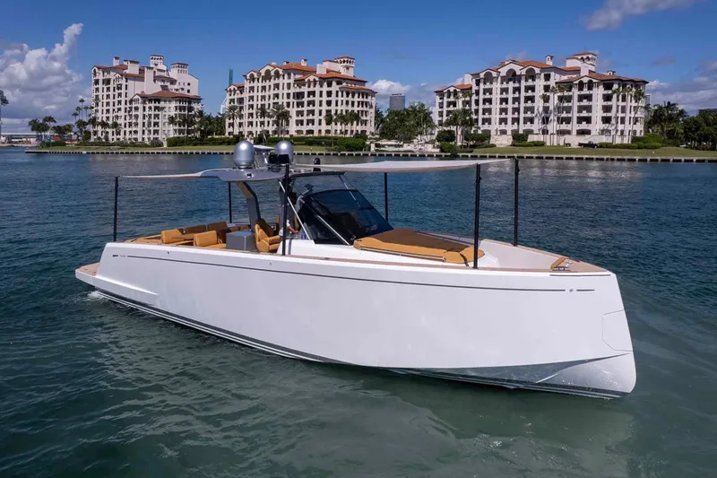 Slide: The Image of 2023 Pardo Yachts 43 cruising near luxury waterfront apartments under a clear blue sky. - 67