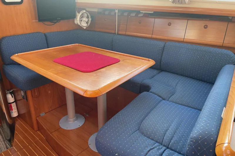 Slide: The Image of Interior of 2003 Jeanneau Sun Odyssey 43 DS with blue cushioned seating and wooden table. - 16