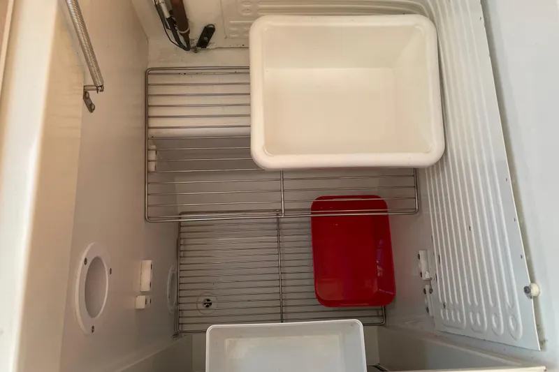 Slide: The Image of Interior of a 2003 Jeanneau Sun Odyssey 43 DS refrigerator with wire racks and containers. - 33