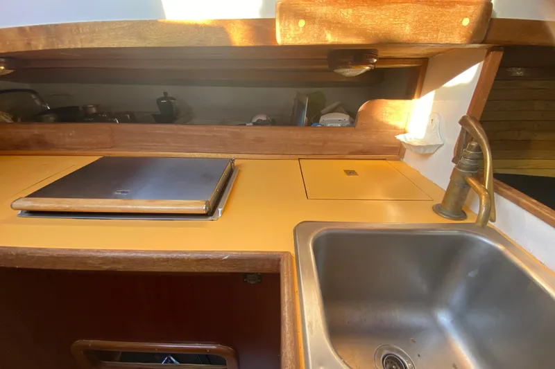 Slide: The Image of 1978 Bristol Channel Cutter 28 galley with sink, stove, and wooden cabinetry. - 24