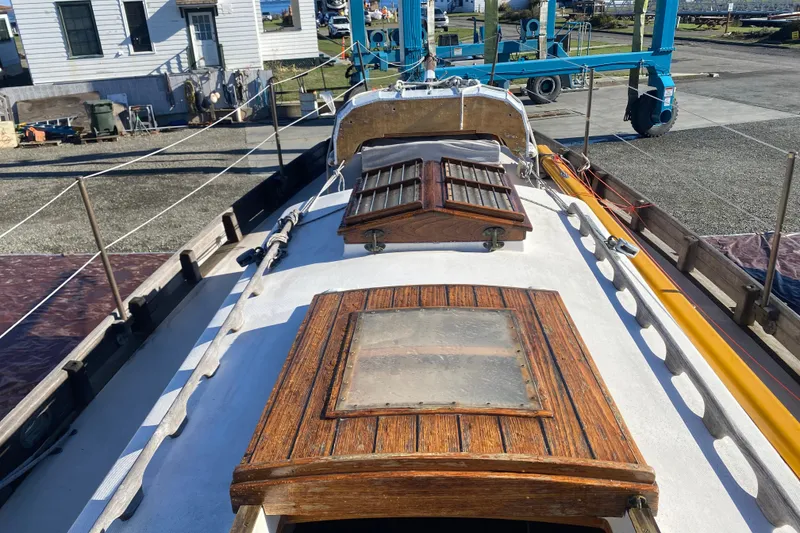 Slide: The Image of 1978 Bristol Channel Cutter 28 sailboat deck with wooden hatches and marina background. - 8