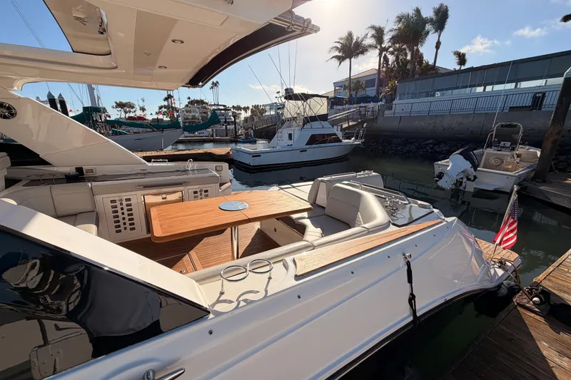 Slide: The Image of 2021 Sea Ray SLX 400 yacht docked, featuring a spacious seating area and wooden table. - 12