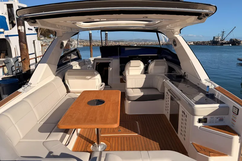 Slide: The Image of 2021 Sea Ray SLX 400 boat interior with seating, table, and kitchenette by the water. - 20