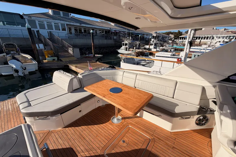 Slide: The Image of 2021 Sea Ray SLX 400 boat interior with elegant seating and wooden table at marina. - 25