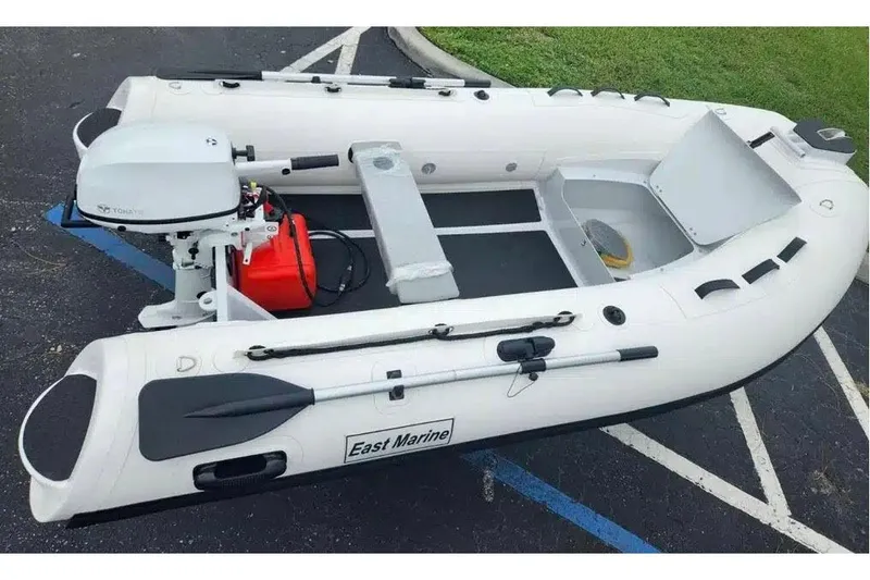 The Image of Manufacturer Provided Image: Inflatable East Marine 300 boat, 2025 model, with outboard motor and oars on pavement. - 0