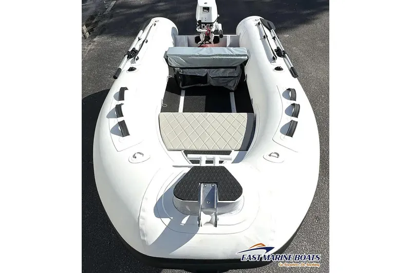 Slide: The Image of Manufacturer Provided Image: 2025 East Marine 300 inflatable boat, top view, featuring seating and motor, on pavement. - 2