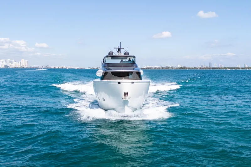 Slide: The Image of 2019 Sanlorenzo SX76 yacht cruising on a sunny day with city skyline in background. - 2