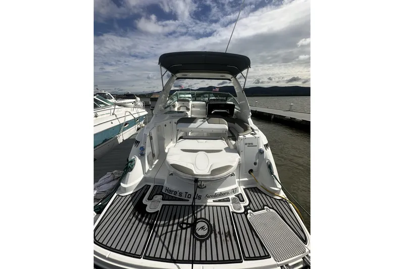 Slide: The Image of 2016 Monterey 295 Sport Yacht docked, showcasing spacious deck and seating under cloudy sky. - 2