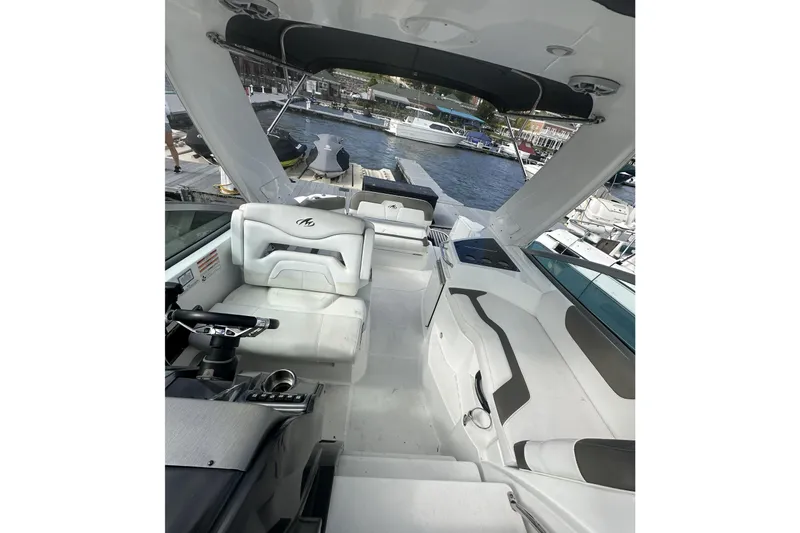 Slide: The Image of 2016 Monterey 295 Sport Yacht interior with white seating and helm, docked by the water. - 7