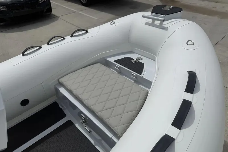 Slide: The Image of 2026 East Marine 320 inflatable boat with Tohatsu engine, displayed indoors on wooden flooring. - 2