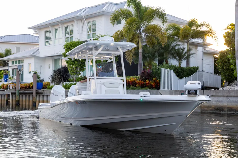 Slide: The Image of 2022 Caymas 28 HB Twin boat cruising near waterfront home with palm trees. - 1