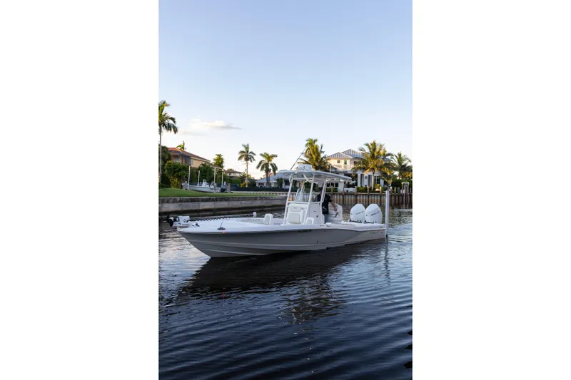 Slide: The Image of 2022 Caymas 28 HB Twin boat cruising on a calm waterway with palm trees in the background. - 24