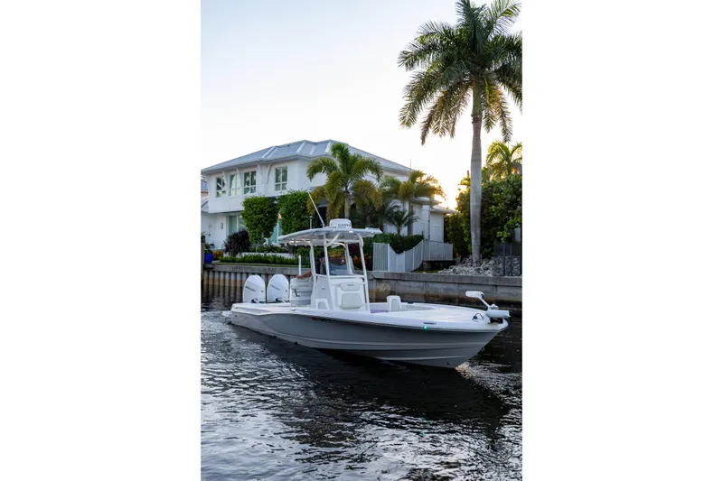 Slide: The Image of 2022 Caymas 28 HB Twin boat cruising near waterfront home with palm trees. - 28