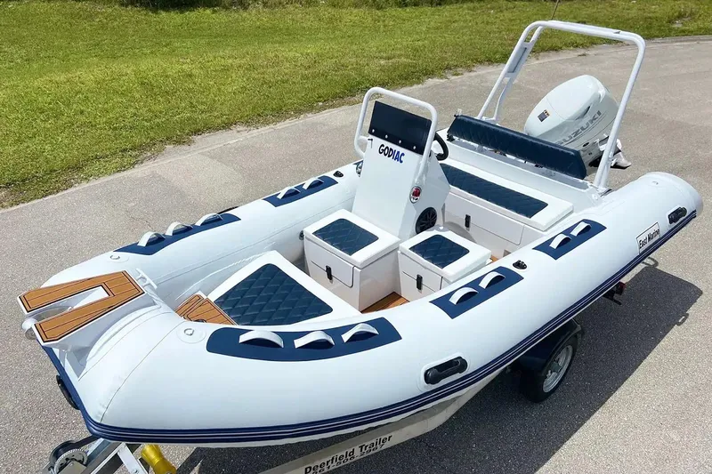 The Image of Manufacturer Provided Image: 2025 East Marine 420 inflatable boat with seating, storage, and outboard motor on a trailer. - 0