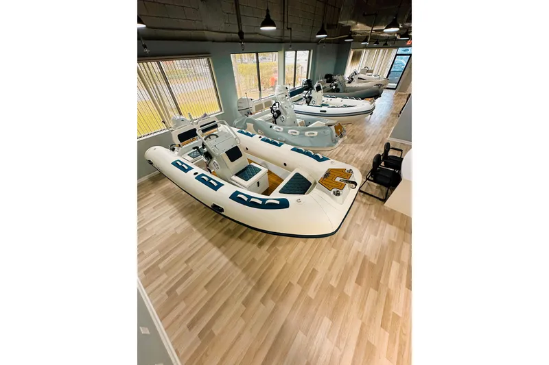 Slide: The Image of Showroom displaying 2026 East Marine 420 LUXURY inflatable boats on wooden flooring. - 13