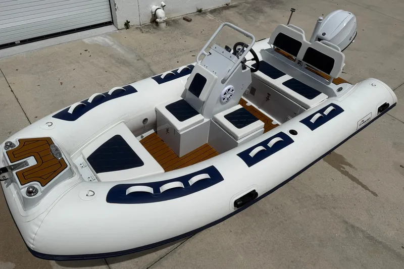 Slide: The Image of 2026 East Marine 420 LUXURY inflatable boat with seating and steering console on concrete surface. - 8