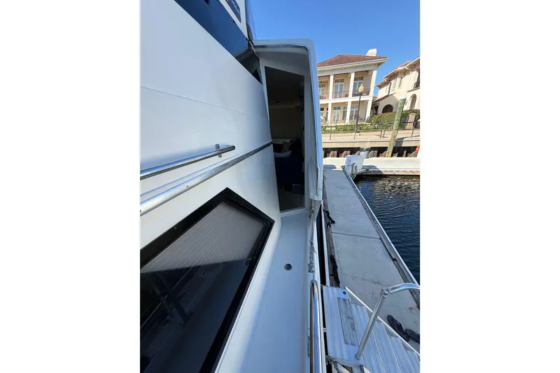 Slide: The Image of 1991 Californian 55 Cockpit Motor Yacht docked, showcasing sleek side view and marina backdrop. - 13