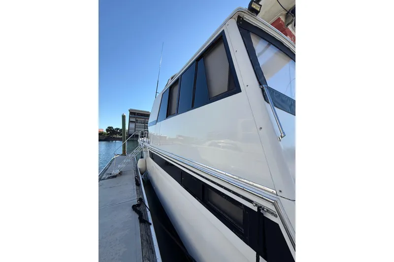 Slide: The Image of 1991 Californian 55 Cockpit Motor Yacht docked in marina, modern buildings in background. - 8