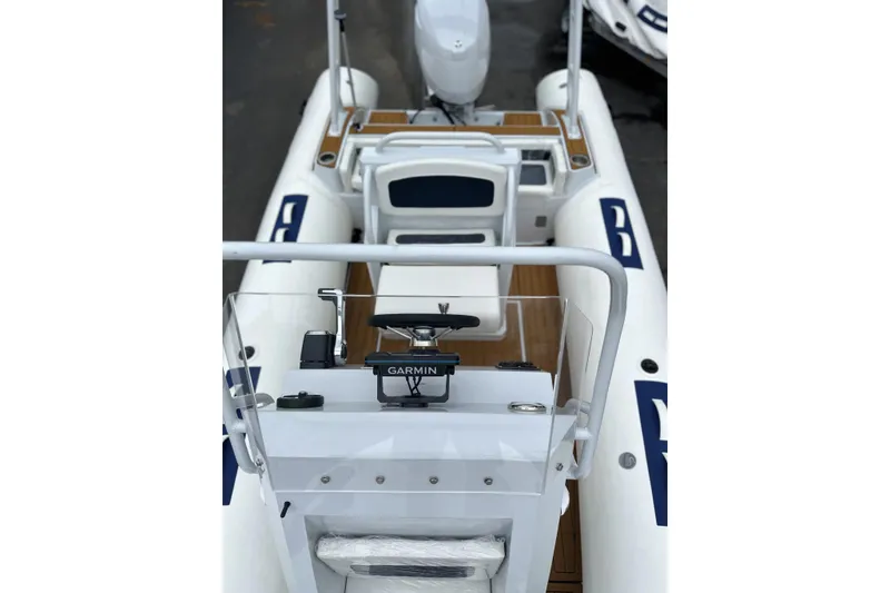 Slide: The Image of 2026 East Marine 560 boat interior with Garmin navigation system, white seating, and wooden flooring. - 12
