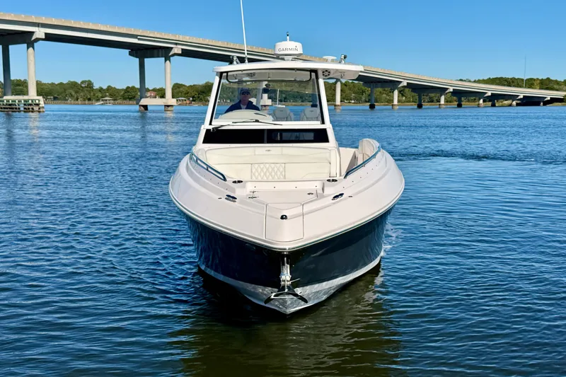 Slide: The Image of 2021 Regal 33 SAV boat on calm water near a bridge under clear blue sky. - 2