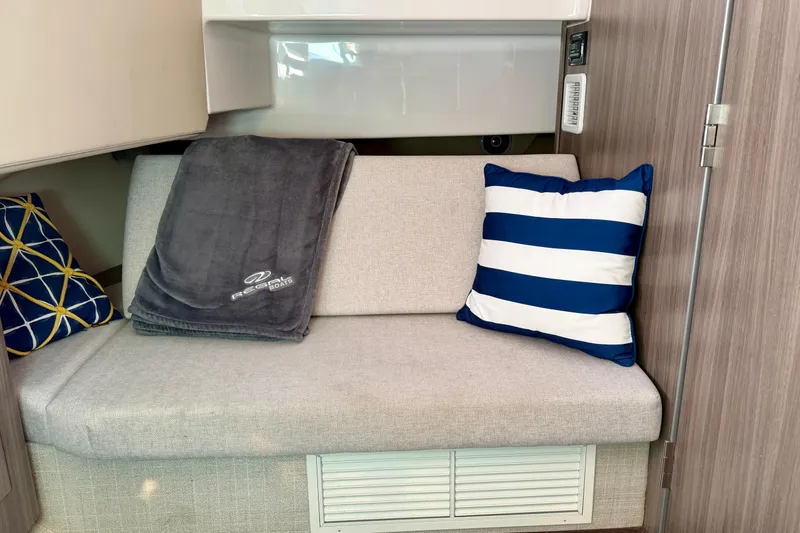 Slide: The Image of 2021 Regal 33 SAV interior with cozy seating, striped pillow, and branded blanket. - 33