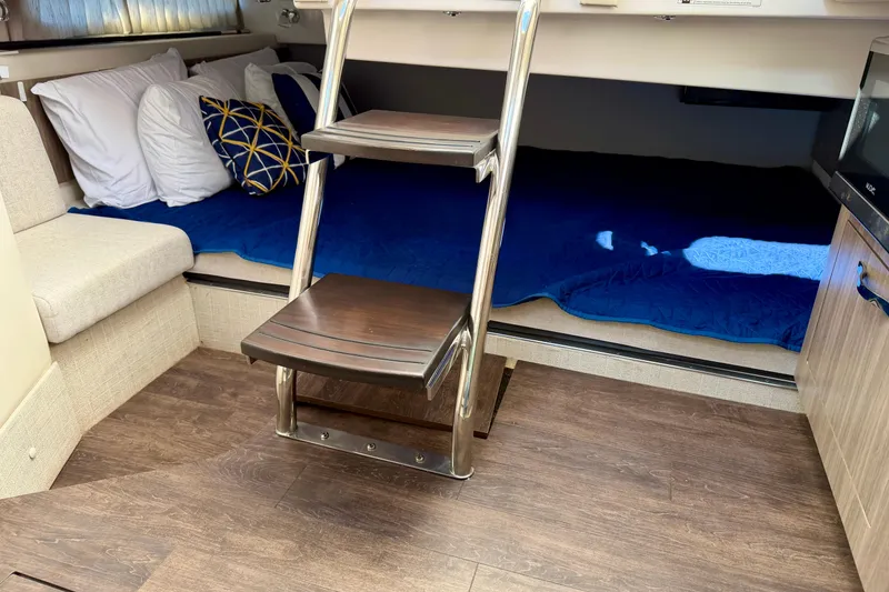 Slide: The Image of Interior of 2021 Regal 33 SAV boat with cozy bedding and wooden steps. - 35