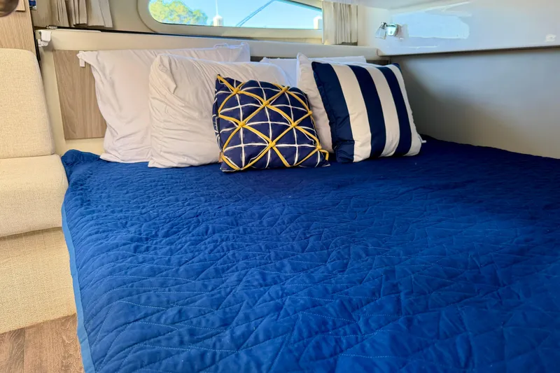 Slide: The Image of Cozy cabin bed with blue quilt and decorative pillows on 2021 Regal 33 SAV boat. - 37