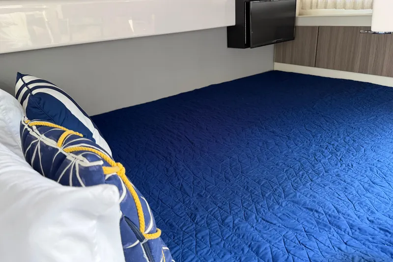 Slide: The Image of Interior cabin of 2021 Regal 33 SAV with blue bedding and decorative pillows. - 38