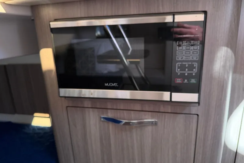 Slide: The Image of Microwave in 2021 Regal 33 SAV boat interior, featuring sleek wood cabinetry. - 40