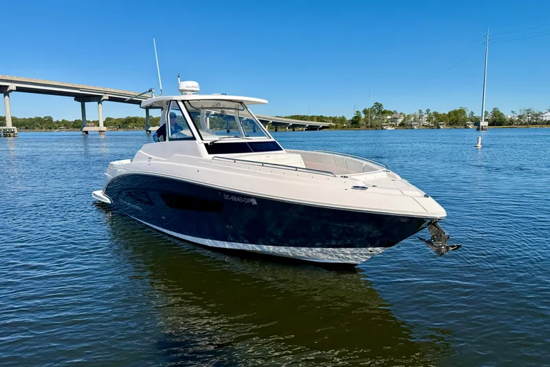 Slide: The Image of 2021 Regal 33 SAV boat on calm water near a bridge under clear blue sky. - 6