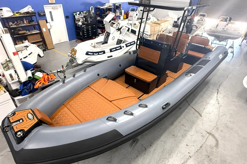 The Image of 2026 East Marine 700 inflatable boat with orange seating in a workshop setting. - 0
