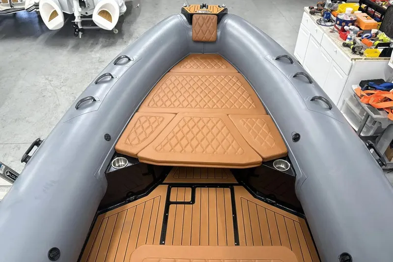 Slide: The Image of Manufacturer Provided Image: 2025 East Marine 700 boat interior with tan cushioned seating and gray inflatable sides. - 6