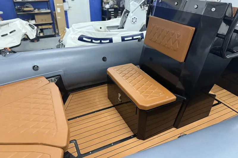 Slide: The Image of Manufacturer Provided Image: 2025 East Marine 700 boat interior with tan cushioned seating and wood-style flooring. - 7