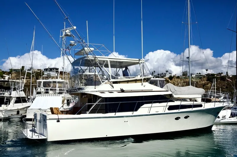 Slide: The Image of 2002 Mikelson 50 Sportfisher yacht docked in a marina under clear blue skies. - 12