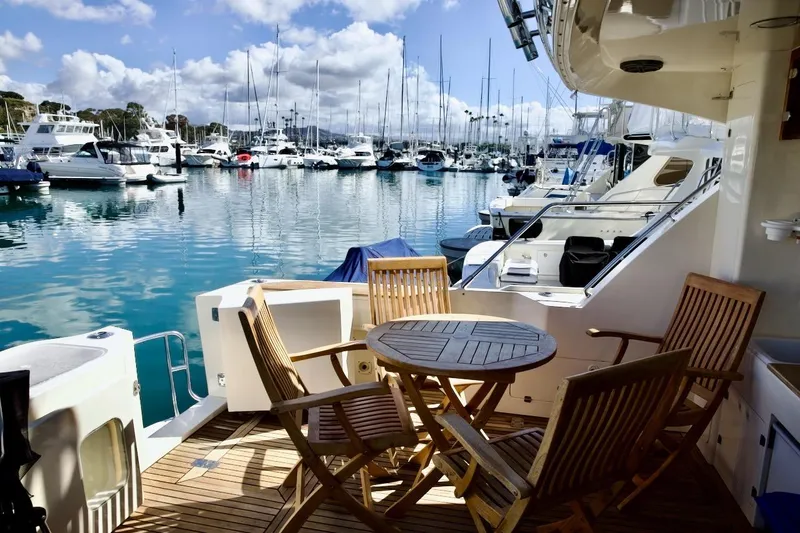 Slide: The Image of 2002 Mikelson 50 Sportfisher yacht with wooden deck chairs in a marina setting. - 33
